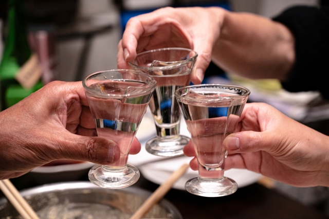 焼酎の入ったグラスで乾杯する3人の手元